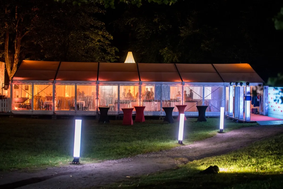 Beleuchtete LED-Säulen im Freien am Abend, Zelt im Hintergrund