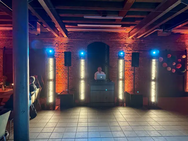 DJ-Pult in einer Halle mit Backsteingewölbe und blauem Scheinwerferlicht