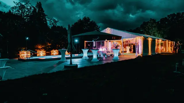 Empfang am Pool bei Nacht, warm beleuchtetes Zelt im Hintergrund