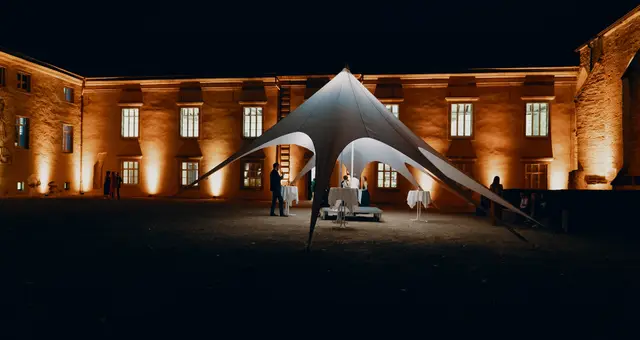 Sternförmiges Empfangszelt vor historischem Gebäude bei Nacht
