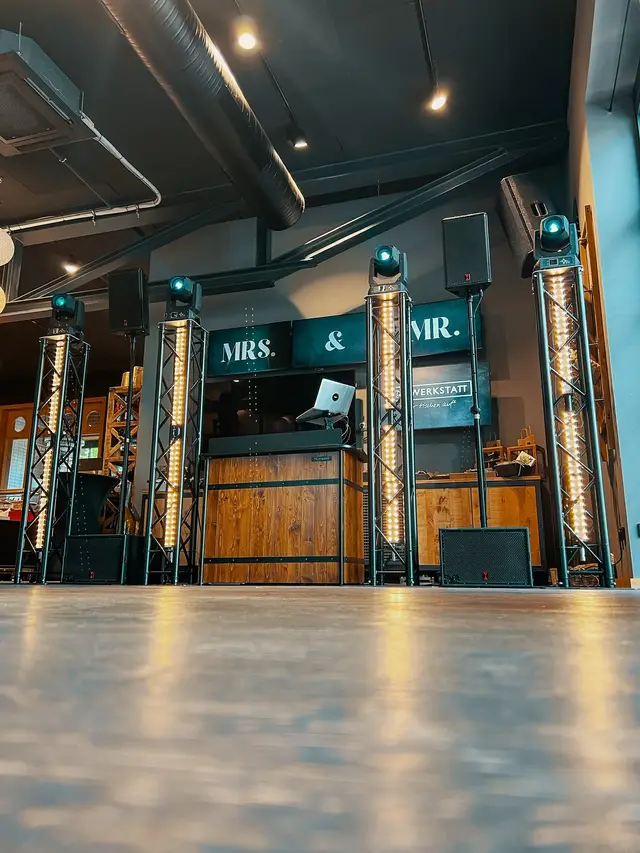 Vier Truss Tower black neben dem DJ-Pult, dahinter Bildschirme mit MRS. und MR.