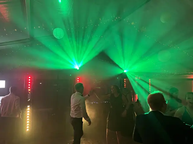 Grüne Lichtstrahlen über einer Tanzfläche im Zelt, Gäste tanzen