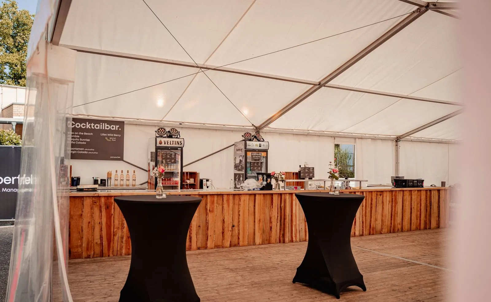 Aufgebaute Cocktailbar in einem Festzelt, mit Getränkekühlschränken und Zapfanlage